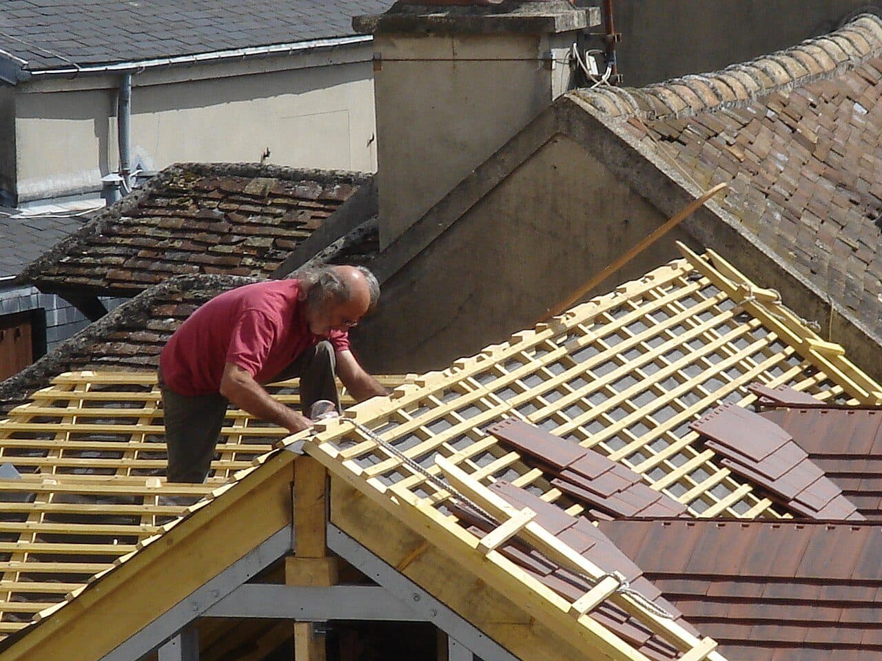 Roofer fixing timber battens on an open roof frame