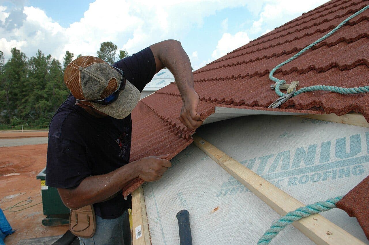Roofer fitting red roof tiles above new underlayment