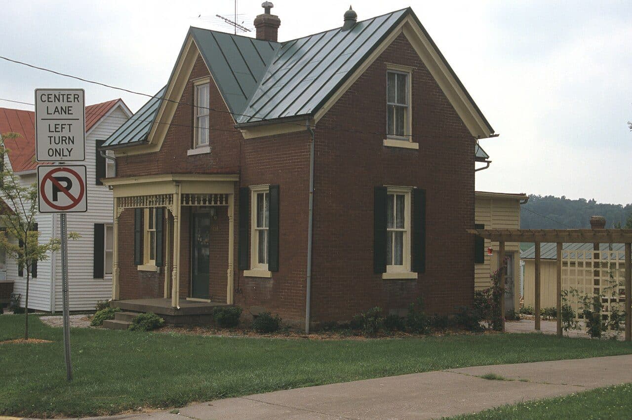 Red brick two-story house with a green standing-seam metal roof