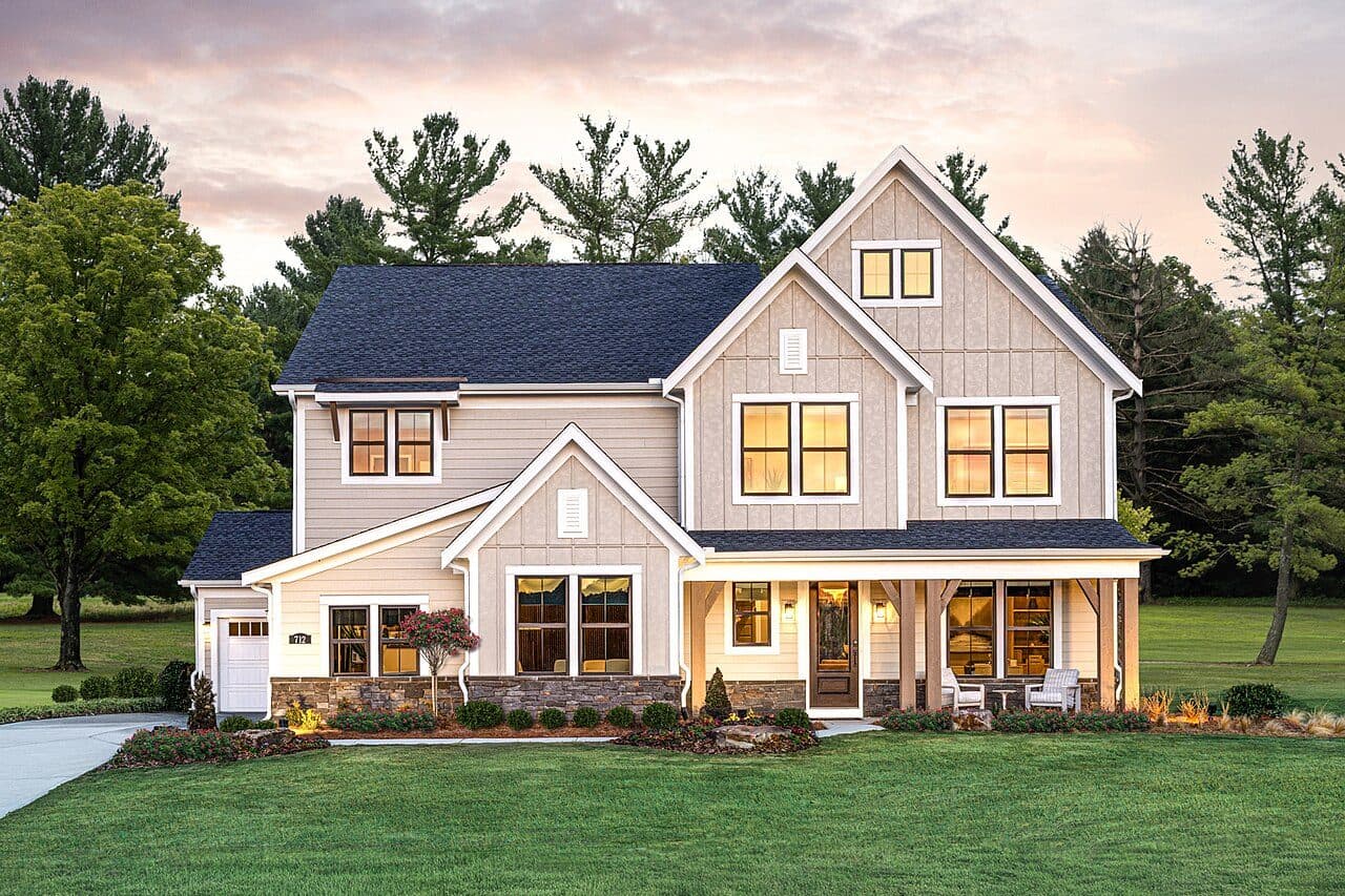 White modern farmhouse with a dark charcoal shingle roof at dusk