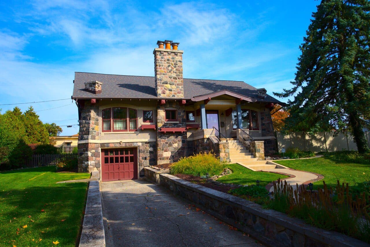 Stone craftsman bungalow with low-slope roof and a garage below