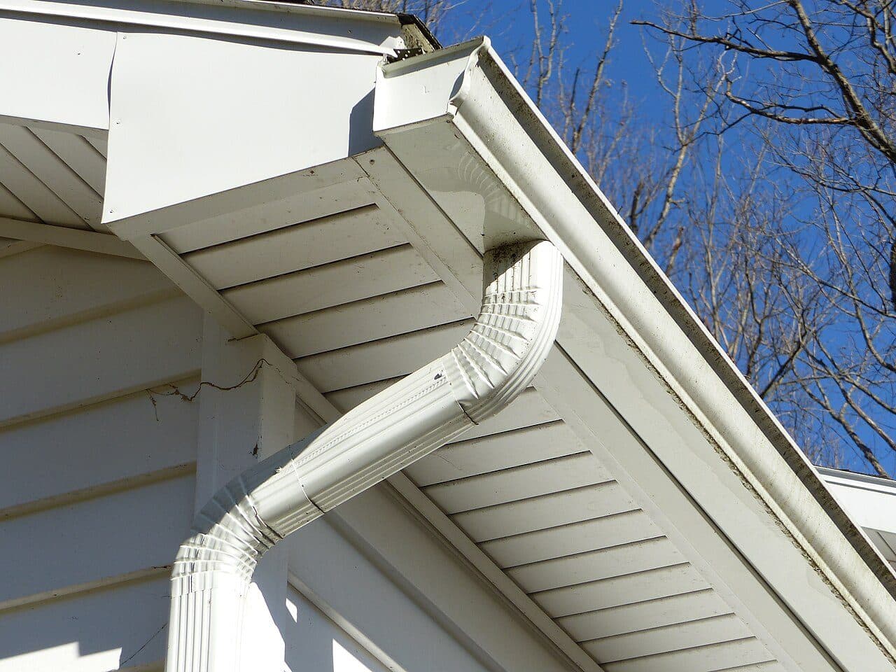 White seamless aluminum gutter and downspout on a house eave